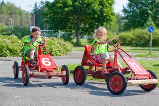 Kaksi lasta ajaa polkuautoilla liikennepuistossa
