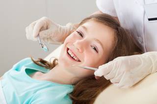 Tyttö hymyilee hammaslääkärin tutkimuksessa