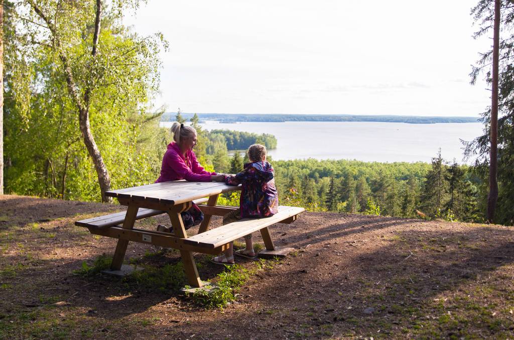 Nainen ja tyttö istuvat pöydän ääressä ja katsevat maisemia Rapolanharjulla.