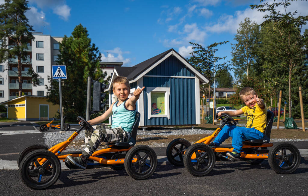 Liikennepuisto pojat ajavat leikkiautoilla.