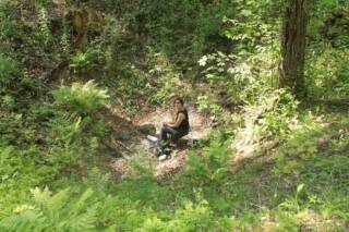 Nainen istuu metsässä.
