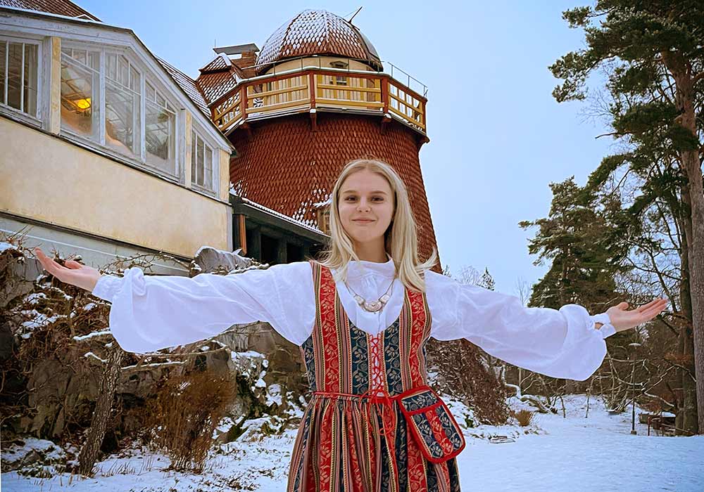 Nainen Sääksmäen kansallispuku päällä Visavuoren pihassa talvella.