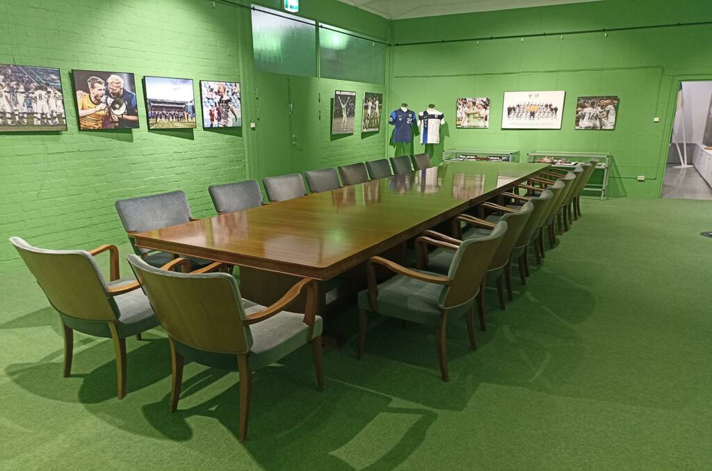 Kokoustila, jossa vihreät seinät ja iso kokouspöytä ja ympärillä tuoleja.