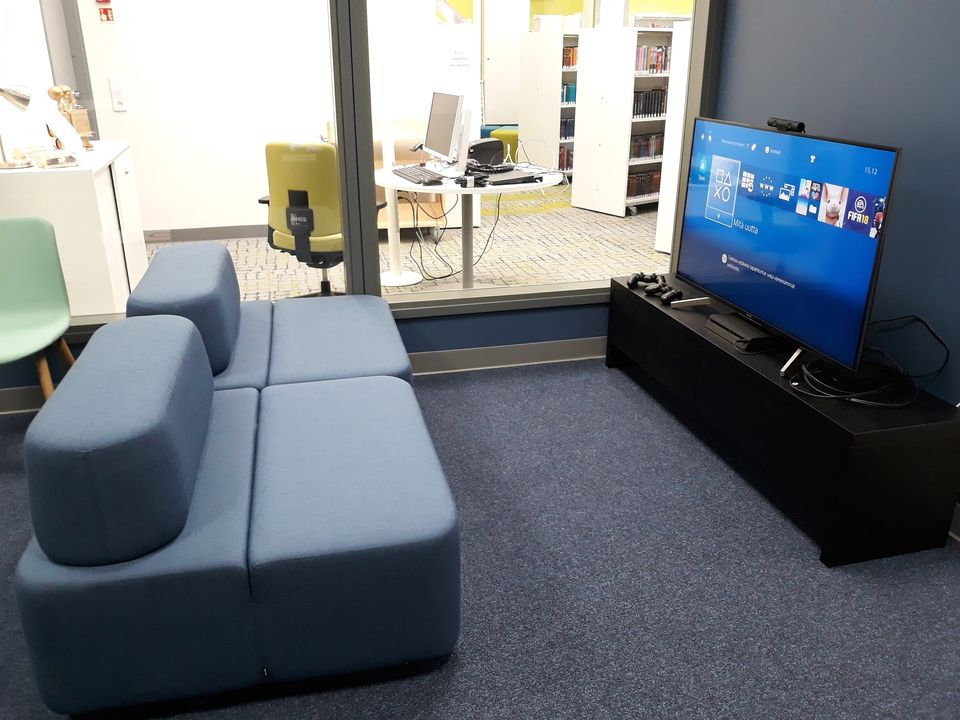 Pelitila Valkeakosken kirjastossa, kaksi nojatuolia ja televisio, jossa Playstation.