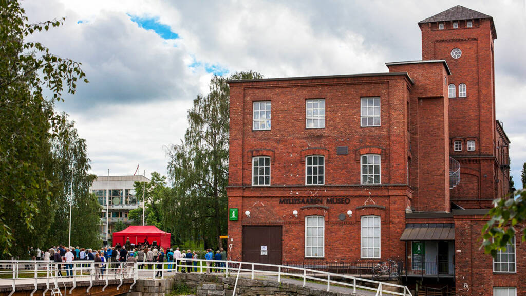 Myllysaaren museo, jonka pihalla on ihmisiä ja punainen myyntikoju.