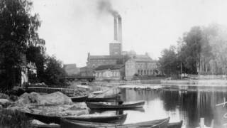 Mustavalkoinen kuva tehtaasta ja kanavasta.