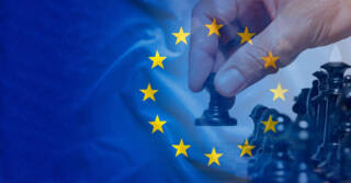 EU:n lippu ja shakkinappula ihmisen kädessä.