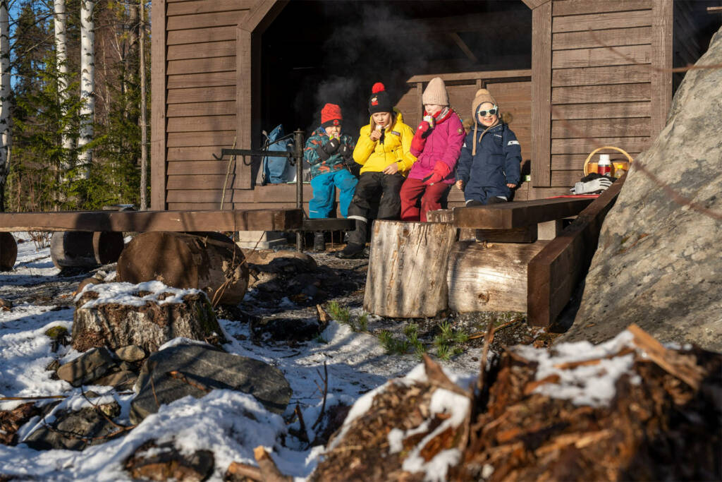 Neljä lasta istuu laavulla ja syövät eväitä Pappilanniemessä Valkeakoskella.