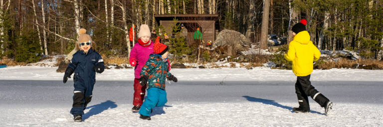 Lapset juoksevat jäällä aurinkoisella säällä Pappilanniemen laavulla.