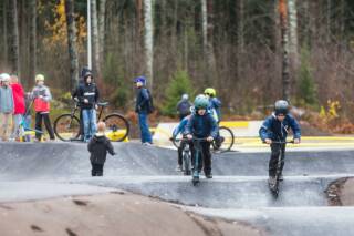 Kids on kick scooters on the pump track.