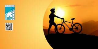 Pyöräilijän tumma hahmo auringonlaskua vasten.