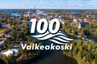 Syksyinen ilmakuva, jossa Valkeakoski 100 logo päällä.