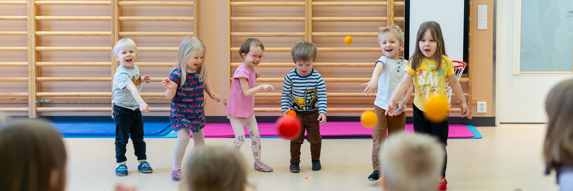 The children are playing with balls in the gymnasium.