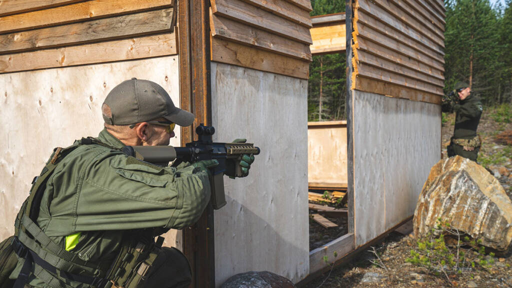 Mies tähtää airsoft-aseella rakennuksen vieressä.