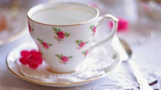 pöydällä kahvikuppi jossa ruusun kuvia.