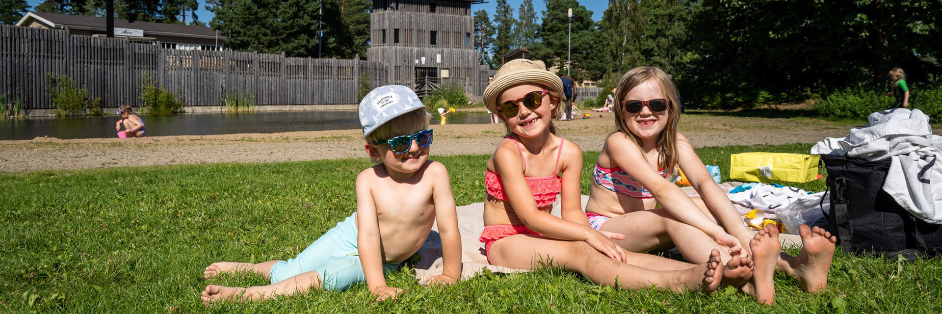 Kids sitting on a grass on the Apia beach.