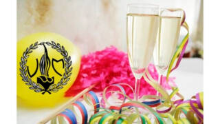 Kaksi kuohuviinilasia, ilmapallo ja serpentiinejä.