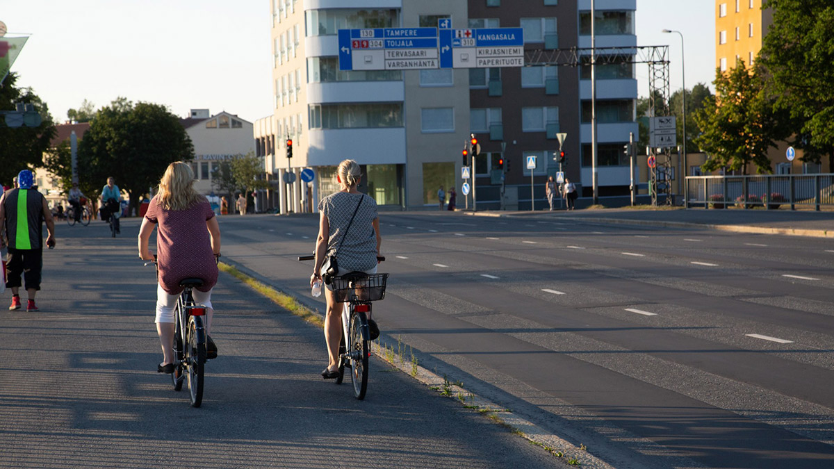 Kaksi naista pyöräilemässä Valkeakosken kaupungin keskustassa.