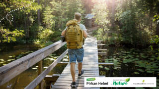 Henkilö kävelee rinkka selässään puisella kävelysillalla.