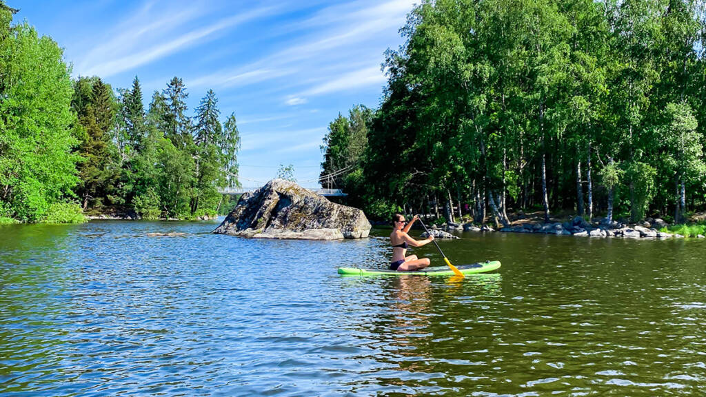 Nainen suppailee vesillä.