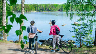 Kaksi naista pyörien kanssa järvenrannassa.