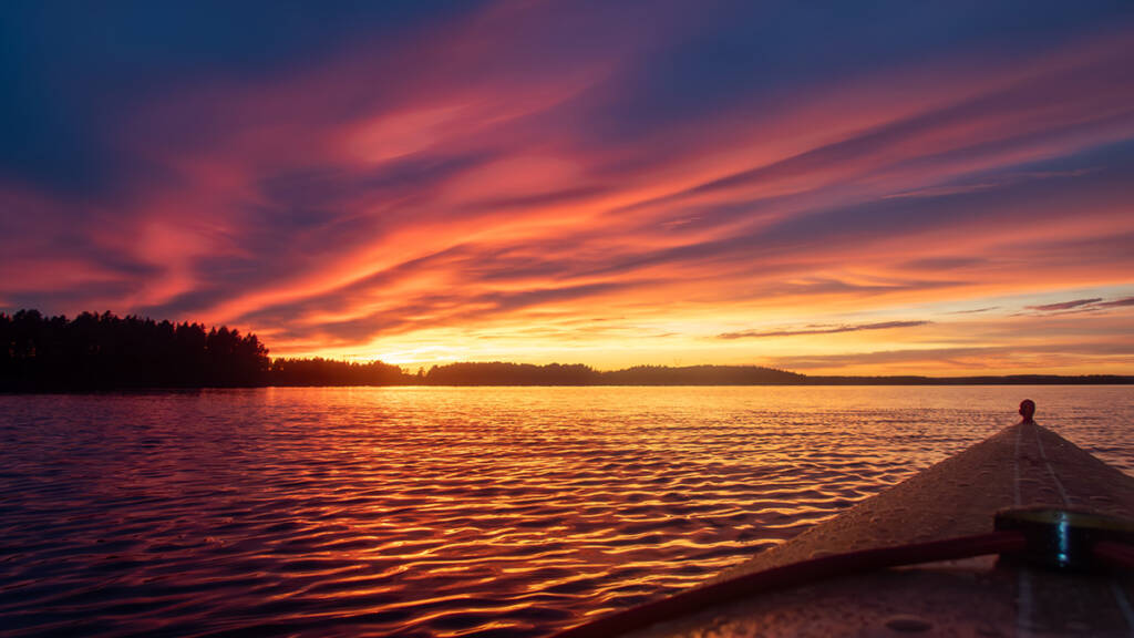 kajakin kärki auringonlaskua vasten vesillä.