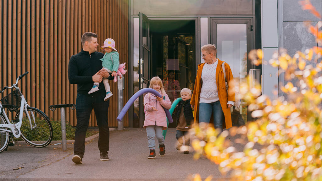 Perhe kävelee uimahallin edessä.