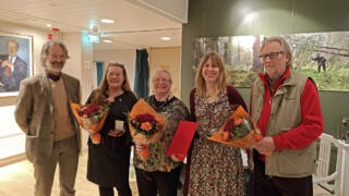 Kaksi miestä ja kaksi naista seisovat rivissä kukkakimppujen kanssa.