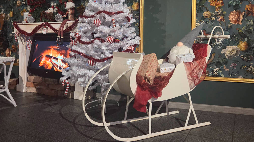 Somistettu kelkka ja joulukuusi kahvilassa.