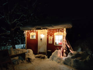 Punainen tupa jouluvaloineen.