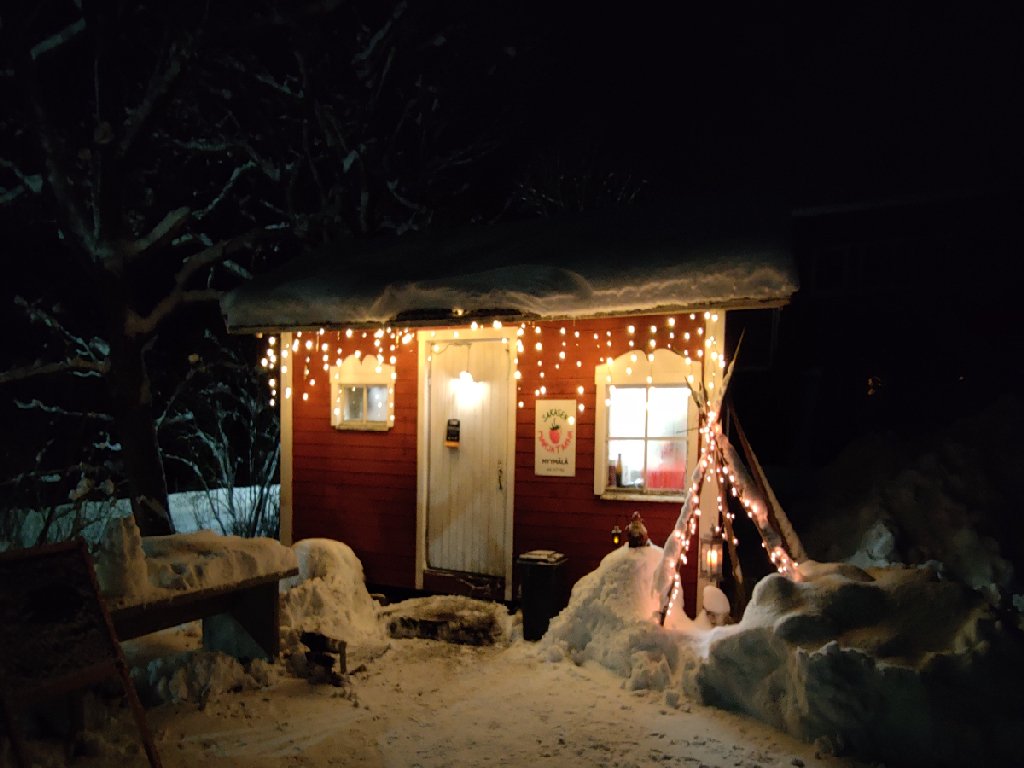 Punainen tupa jouluvaloineen.