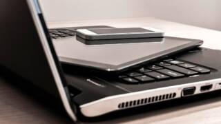 Kannettava tietokone, tabletti ja matkapuhelin pinottuina päällekäin.