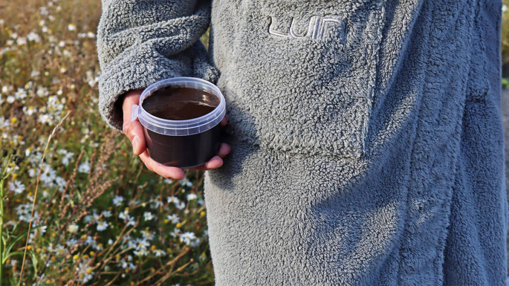 Kuva jossa kylpytakissa oleva henkilö pitää purkkia kädessään.