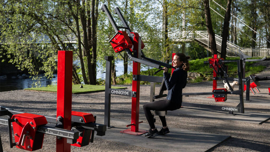 Nainen kuntoilee ulkokuntoilusalilla riippusillan läheisyydessä.