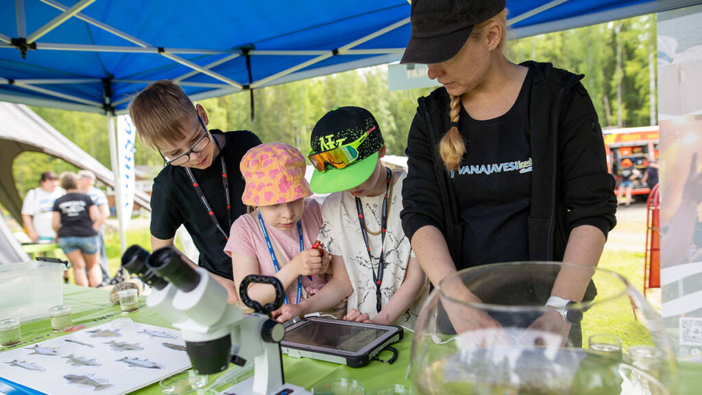 Lapset tutkivat aikuisen ohjauksessa vesieliöit mikroskopilla.