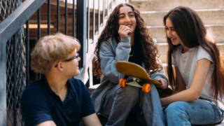 Kolme nuorta istuu portailla.