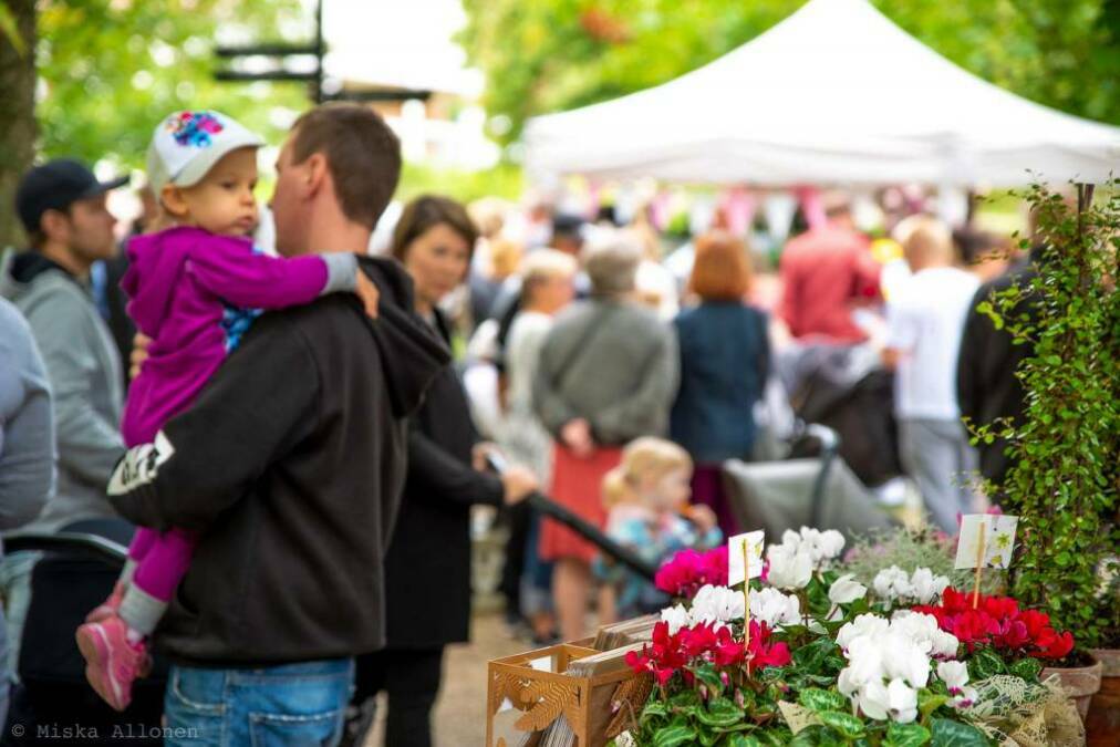 Aikuisia ja lapsia kulkemassa markkinoilla.