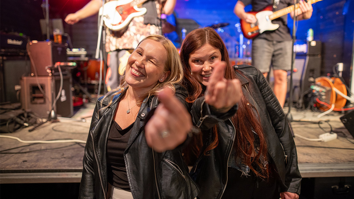 kaksi naista poseeraa keikalla.