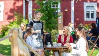 Ihmisiä istuu Mokkapirtin kesäterassilla ulkona kahvilla.
