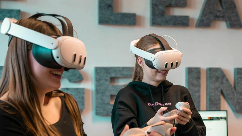 kaksi nuorta naista vr-lasit päässä pelaamassa.