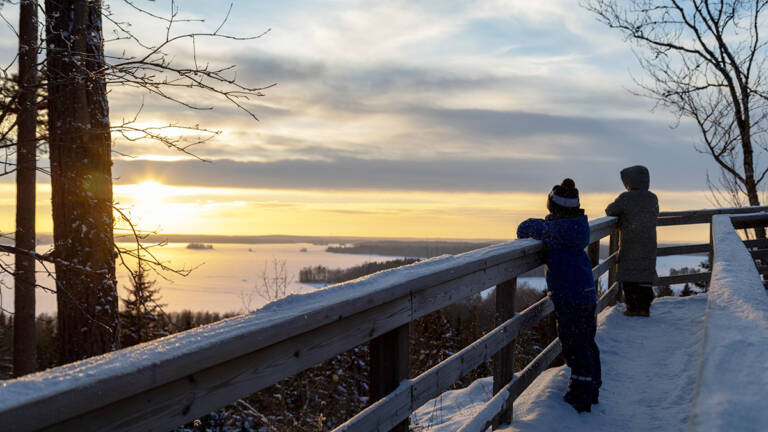 Lapset katselevat auringonlaskua Rapolanharjun näköalatasanteella.
