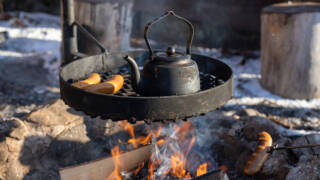 Pannukahvit ja makkaroita paistumassa nuotiolla.
