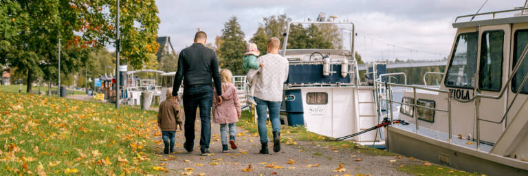 Perhe kävelee kanavan rannassa syksyllä.