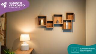 Huone, missä lamppu pöydällä ja seinällä tauluja.