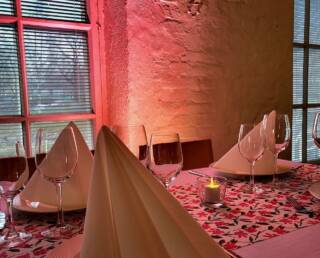 Pinkissä valaistuksessa pöydälle on katettuna viinilaseja ja lautasliinoja.