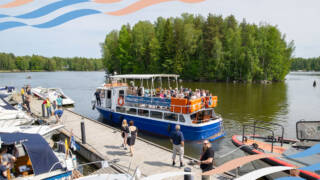 Pirkka Lines -laiva Linnosaaren edessä ja kuvassa Vesistöviikon aalto-grafiikkaa.