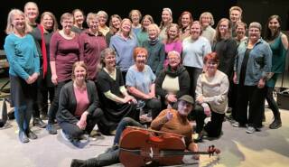 Ryhmä naisia seisomassa ja edessä on mies kyljellään sellon kanssa.