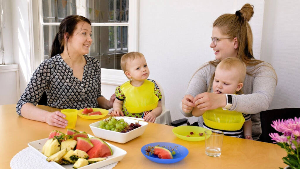 Kaksi lasta ja kaksi aikuista pöydän ääressä syömässä.