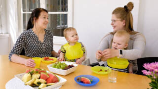 Kaksi lasta ja kaksi aikuista pöydän ääressä syömässä.