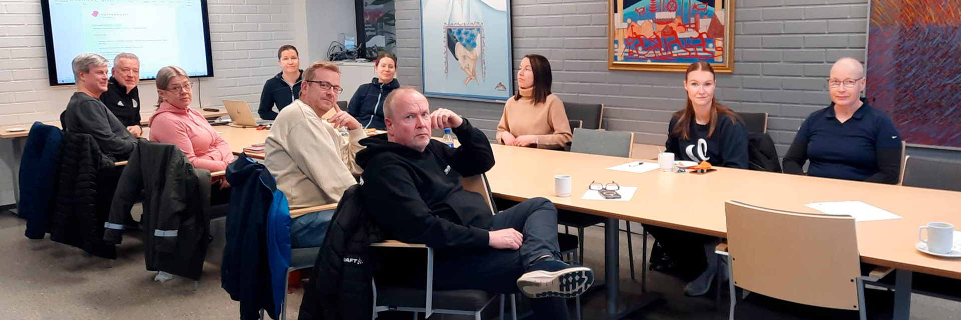 Ryhmäkuva henkilöistä istumassa pöydän molemmin puolin.